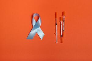 médico concepto 14 para noviembre. plano laico de insulina jeringas y azul satín cinta, simbólico arco color de mundo diabetes conciencia día, aislado terminado naranja de colores antecedentes con Copiar espacio para anuncio foto