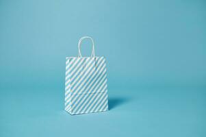 un papel bolso con blanco azul rayas en un azul antecedentes con Copiar espacio para promoción. publicidad foto