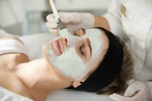 Closeup of cosmetologist applying an alginic mask on a beautiful woman face photo