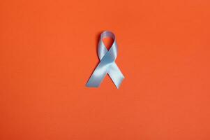 World diabetes day awareness concept. Flat lay of a blue satin ribbon, symbolic bow color raising awareness in diabetes day on orange colored background with copy space for ad, 14 November. photo