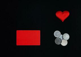 un horizontal rojo rectángulo, rojo corazón y dinero monedas en un negro antecedentes san valentin día concepto. borde, Copiar espacio, parte superior vista, celebracion, fiesta foto