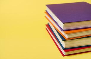 Stack of multicolored books on yellow surface background with copy space for text. Teacher's Day concept, Knowledge, literature ,reading, erudition photo