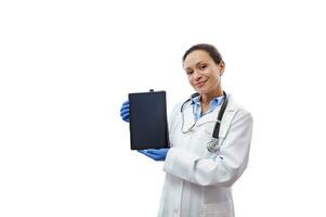 Smiling woman doctor holding tablet near her face and showing the screen to the camera isolated on white background photo