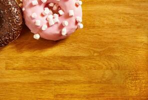 Donuts with various glaze on a wooden surface. Flat lay composition with copy space on a wooden background photo