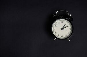 Flat lay. Monochrome composition with a vintage alarm clock on black background with copy space to add text. Back to School and Teachers Day Concepts, Business, Organization, Time Management photo