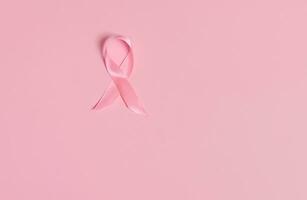 plano laico de un satín rosado cinta conciencia, internacional símbolo de pecho cáncer conciencia mes en octubre. aislado terminado en rosado antecedentes con Copiar espacio .De las mujeres salud cuidado y médico concepto. foto