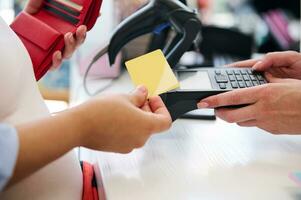 Close-up hands of a customer swiping a mockup golden credit card, making contactless payments using NFC technology. photo