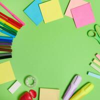 Flat lay composition with stationery office or school supplies scattered in a circle on a light green background with copy space. Back to school concept. photo