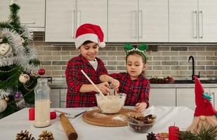 Handsome European children, beautiful preschooler girl and handsome school boy, loving brother and sister preparing Christmas cake dough together in the home kitchen. Happy relationships concept photo