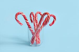 Beautiful minimalistic simple composition with lollipops on transparent glass on blue background with copy space for christmas ad photo