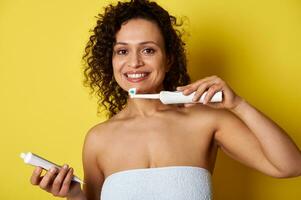 A mixed race woman holding a toothbrush and toothpaste ready to brush her teeth photo