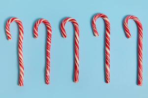 High angle view of Christmas decoration. Flat lay composition of five sweet candy canes, Christmas lollipops lying on blue background with copy space for advertising photo