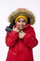 Adorable school-age traveler adventurer handsome boy warming himself hugging thermos, shivering from cold looking at camera isolated on white background. Copy space. Winter leisures, holidays concept photo