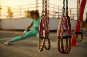 suave atención en suspensión correas en el verano al aire libre campo deportivo en el antecedentes de borroso determinado mezclado carrera atractivo atleta mujer calentamiento arriba antes de peso corporal rutina de ejercicio a puesta de sol foto