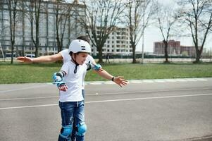 adorable chico en un patineta casco y engranaje es montando un patineta en el calle foto