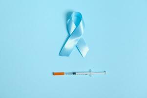 Medical concept 14 for November. Flat lay of insulin syringe and blue satin ribbon, symbolic bow color of World diabetes awareness day, isolated over blue colored background with copy space for ad photo