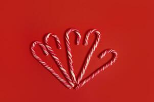 Flat lay of delicious sweet Christmas candy canes on red background with copy space for Christmas advertising. Decoration for 25 december photo