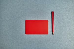 Flat lay with red card and red pencil on a gray background. Copy space photo