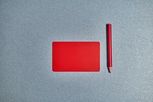 Flat lay with red card and red pencil on a gray background. Copy space photo