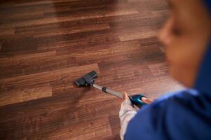 Overhead view of a Muslim woman, housewife, housekeeper vacuuming floor on the living room. Focus on vacuum cleaner photo