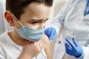 Portrait of a scared boy in a medical mask receiving a dose of infectious disease vaccine photo