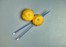 Flat lay of blue spokes and yellow wool yarn on a grey surface photo