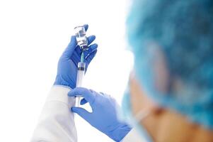 Doctor in protective gloves and workwear filling injection syringe with vaccine isolated white background. View from the back . Vaccination day photo