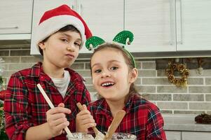 Cheerful cute kids indulge, have fun together in the home kitchen, preparing dough for Christmas cake and cookies. The children themselves are in the kitchen. Happiness is... rejoicing together photo