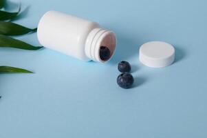 High angle view of blueberries scattered from an opened white container on blue background photo