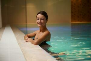 Portrait of beautiful middle aged attractive woman relaxing in swimming thermal pool in luxury wellness spa resort. Purity, hydro therapy, recreation, healthy and active lifestyle concept. Copy space photo