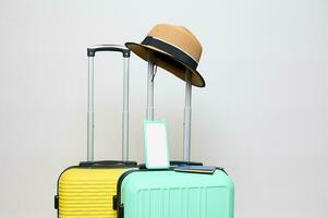 Straw hat on handle of a light green suitcase and modern smartphone with white blank digital screen, isolated background photo