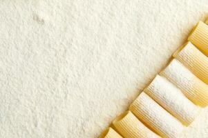 High angle view of neatly arranged whole wheat Italian pasta in a row on a floured surface with copy space for ad photo