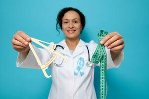 Health care and medical concept, metabolic syndrome disease. Soft focus on caliper and measuring tape in the hands of female doctor nutritionist endocrinologist wearing blue diabetes awareness ribbon photo