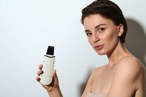 Skin care, cosmetology and beauty spa treatment concept. Attractive naked natural beauty woman posing with ultrasonic peeling device, isolated over white background with copy ad space photo