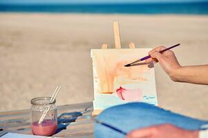 Focus on painting on canvas on the sea background. Hobby concepts . Open air photo