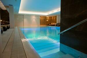 ver de un lujoso moderno interior diseño de un bienestar spa recurso con un térmico nadando piscina con submarino luces y cascada foto