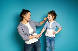 Smiling woman touching her adorable daughter's nose on blue background with copy space photo