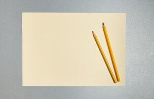 Flat lay. Wooden pencils on a sheet of yellow paper. Top view on a gray background photo