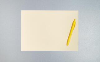 Top view,copy space, flat lay of yellow pen and sheet of paper on a gray surface. Business and office concept photo