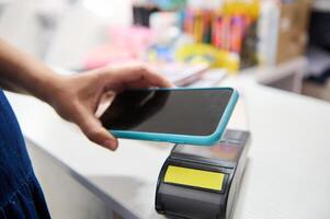 de cerca móvil teléfono en clientes mano pago vía nfc tecnología, participación inteligente móvil teléfono encima un pos Terminal. foto