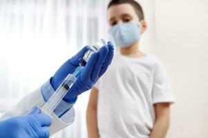 Doctor's hands filling injection syringe with vaccine . Blurred boy on the background photo