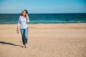joven mezclado carrera mujer con Rizado pelo caminando en el playa foto