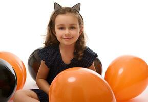 Portrait of cute 4 years old witch girl in Halloween costume with colorful black and orange balloons isolated on white background with copy space. Halloween party. photo