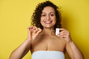 Smiling woman posing to the camera with s dental floss in her hands photo