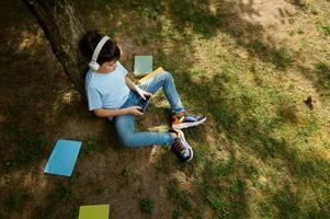 Schoolboy in wireless headphones, top view, playing online video games. Kids Education Digital addiction Entertainment photo