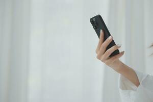 Happy young female in casual clothes smiling and looking at camera while using laptop on bed in bedroom at home photo