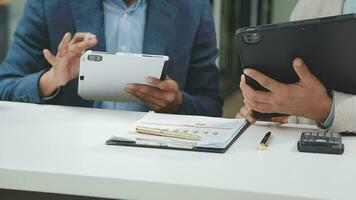 Financial analysts analyze business financial reports on a digital tablet planning investment project during a discussion at a meeting of corporate showing the results of their successful teamwork. video