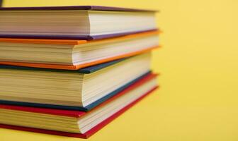 de cerca de apilado multicolor libros en amarillo superficie antecedentes con Copiar espacio para texto. del maestro día concepto, conocimiento, literatura ,lectura, erudición foto