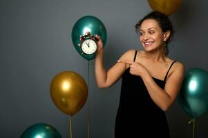 maravilloso mezclado carrera mujer vistiendo un noche vestido, puntos en un alarma reloj aislado terminado gris antecedentes con dorado y verde metálico aire globos Navidad, nuevo año, cumpleaños fiesta, aniversario foto