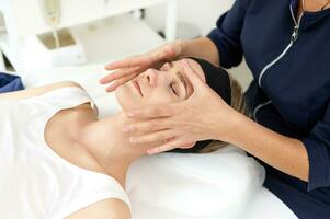 esteticista ejecutando profesional facial masaje en mujer cara a spa clínica foto